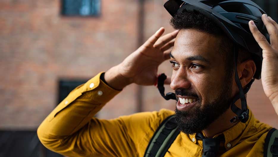 Man cycling reaching for helmet