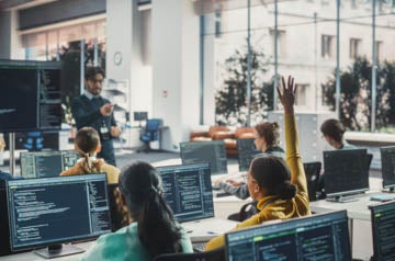 Portrait of a Young Inspired Black Female Student Studying in College with Diverse Classmates. African Girl Asking Teacher a Question. Girl Using Computer to Acquire IT Skills in Class