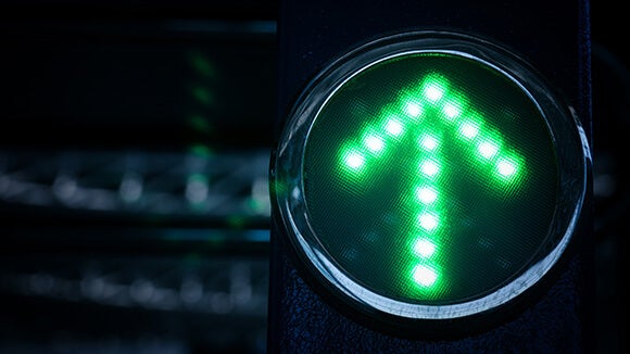 dark blurred background with green arrow traffic light pointing up 