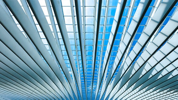 roof of glass building with white lines looking out to blue sky