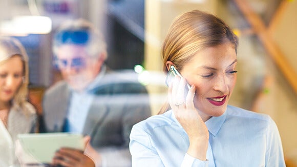 Woman on phone outside of meeting discussing compliance pay rises