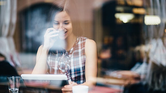 female reading her iPad Female reading her iPad through the window to a coffee shop dressed casually