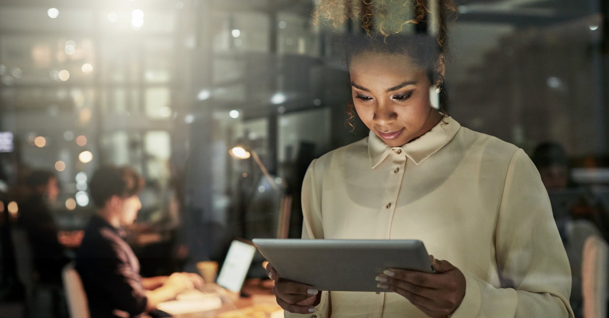 woman on tablet in office woman on tablet in office at night evaluating her skill set