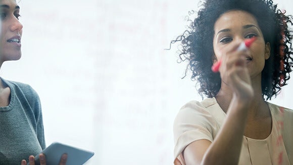 Two female professionals writing Two female professionals writing an effective job description