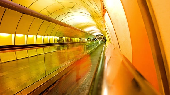 A long orange and yellow tunnel with people walking down the left side