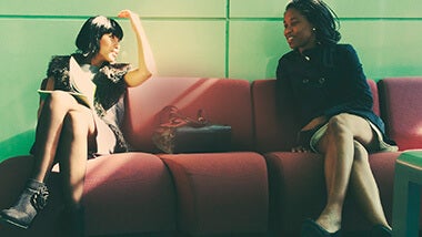 two women discussing an upcoming interview and prepping on a red couch