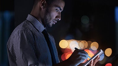Man looking at salary survey on ipad at night
