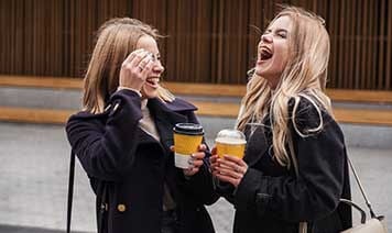 Two women laughing with coffee