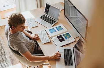 Man sat at desk with multiple screens