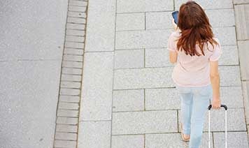 woman walking with phone and suitcase