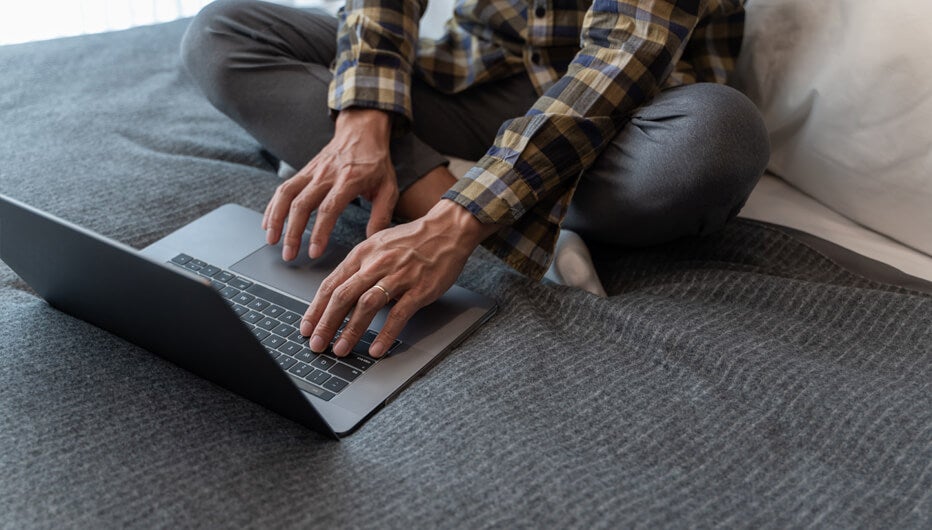 man on bed with laptop