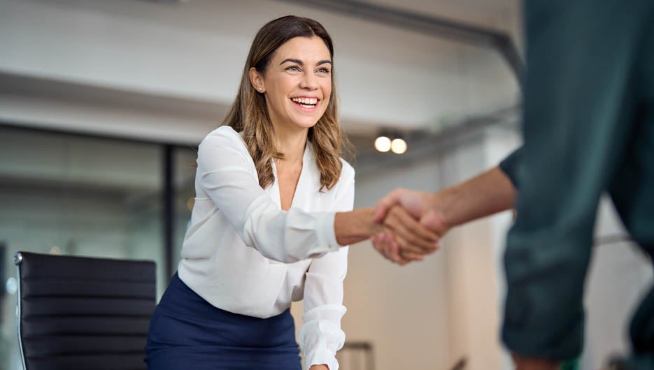 Happy mid aged business woman manager handshaking greeting clien